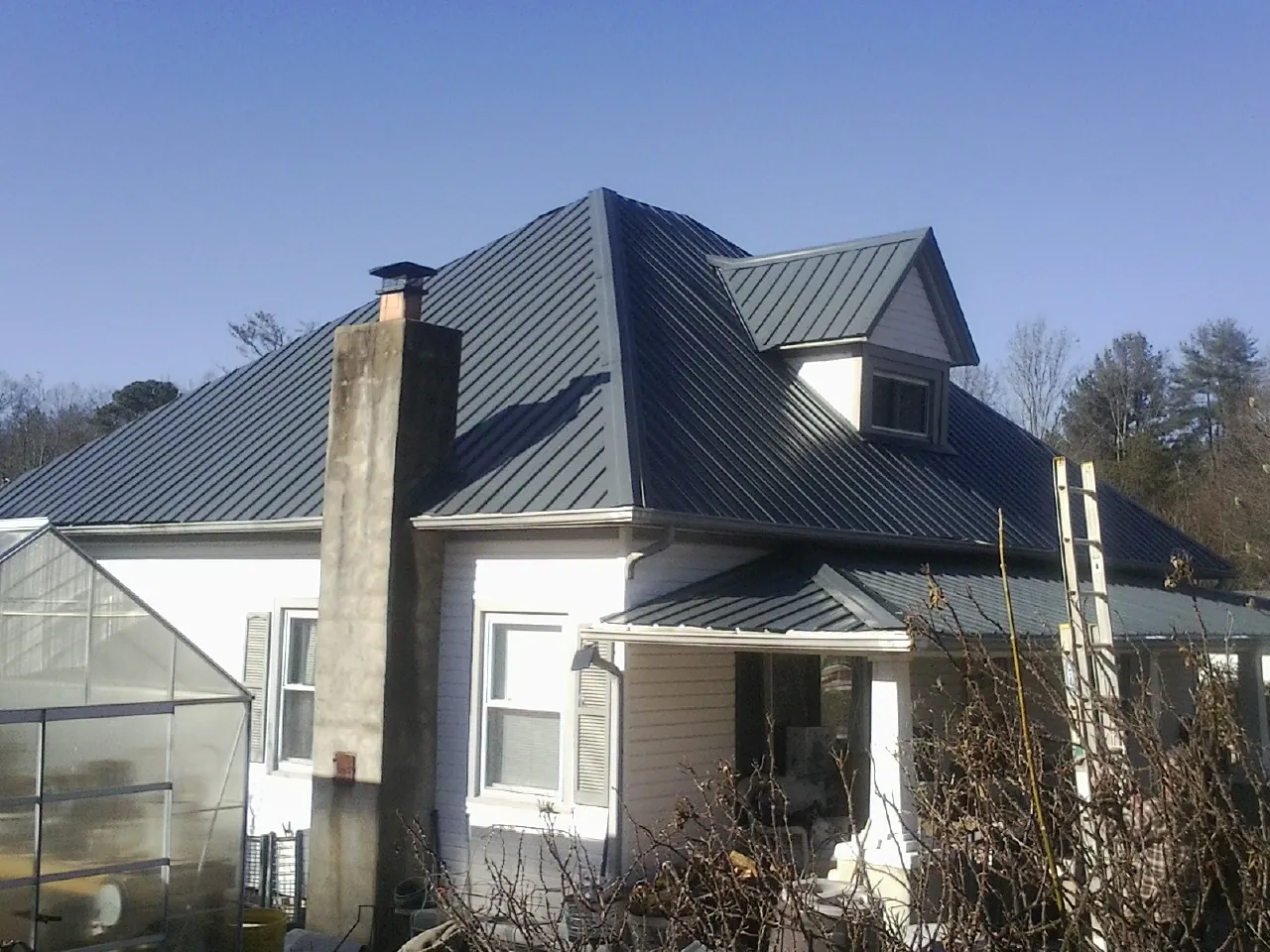 Dark blue standing seam metal roof on a white farmhouse with dormer — Slate & Tile Roof Repair by Roofing Brothers in Drums