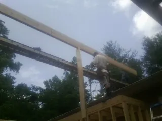 Carpenter setting a ridge beam over a new addition frame — Ice Dam Removal by Roofing Brothers in Drums