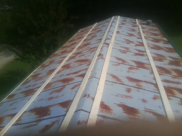 Rusted metal roof panels with new wood purlins before replacement — Storm Damage Roof Repair in Drums by Roofing Brothers