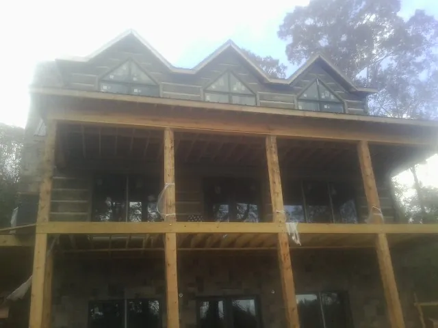 Dormers and porch framing on a large log home under construction — Roof Coating work by our crew in Drums
