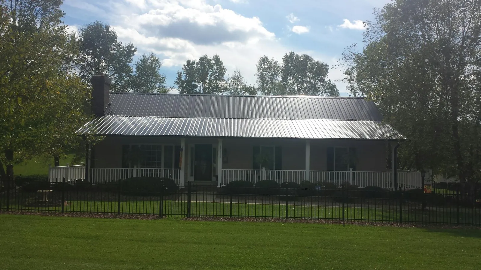 Gray metal roof on a brick ranch with a full width front porch — Gutter Guard Installation work by our crew in Drums