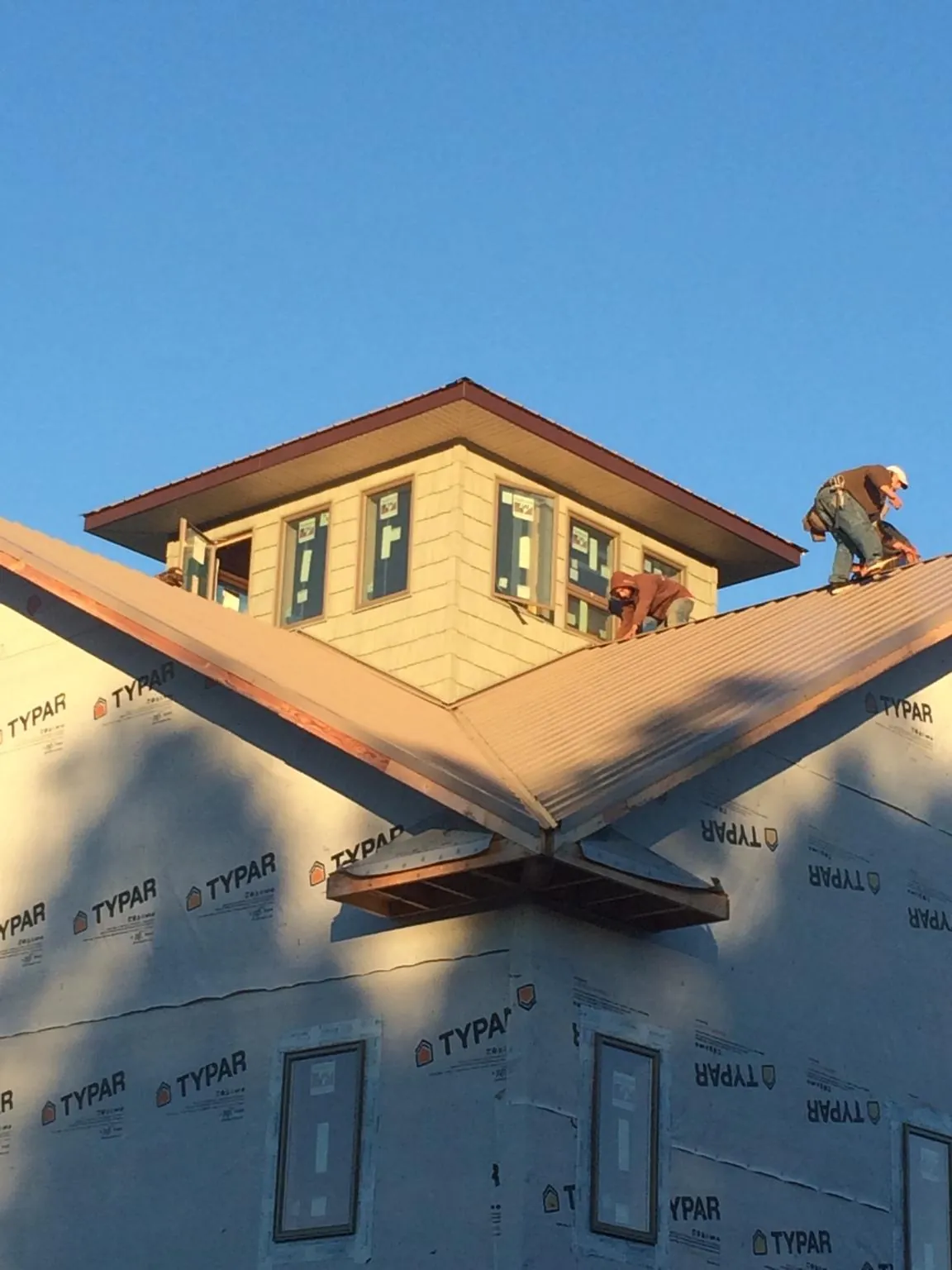 Roofers working around a rooftop cupola on a new metal roof at sunset — Roof Waterproofing in Drums by Roofing Brothers